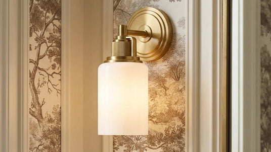 The Claxton Wall Sconce with Milk Glass and a brass finish shown with classic wallpaper in beige and auburn colors.