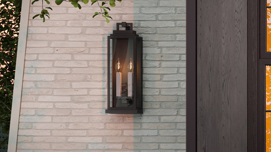 Easton Outdoor Wall Light, Medium 19" Black shown with white candle sleeves at dusk.