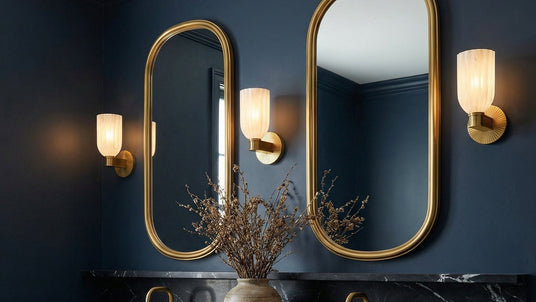 Three Elise Wall Sconces, Brass and Ribbed Strie Glass, shown in a primary bathroom with double vanities painted deep navy blue with gold mirrors.