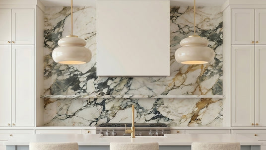 Two Ellsworth 16" Pendant lights in Taupe Crackle Ceramic and Aged Brass hung above a kitchen island with a dramatic marble stone backsplash and floating shelf.