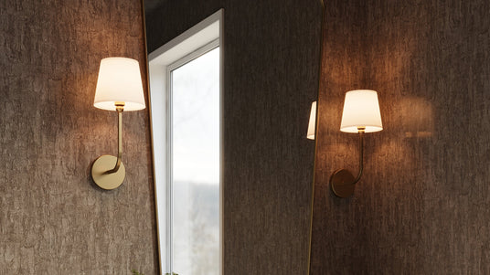 Two Elowen Wall Sconces in Aged Brass in a powder room with grasscloth wallpaper and a brass organic modern shaped mirror.