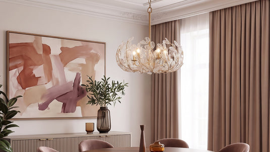 The Esme Chandelier 24", in Soft Brass and Clear Glass, hung above a round sining table with seating for six in a modern room with abstract art.