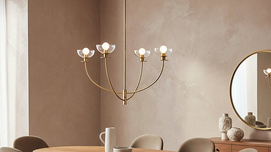 Bella 4 Light Chandelier in brushed brass in a dining room with blush toned plaster walls and light oak furniture.
