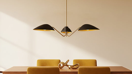 Jade three light mantis style modern chandelier in black and brass above a walnut dining table with marigold velvet chairs