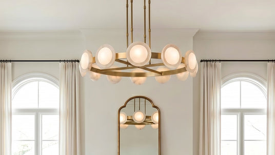 The Osmund LED Chandelier 50", Vintage Brass and Alabaster finish, shown in a classic transitional living room will tall ceilings and arched cased windows.