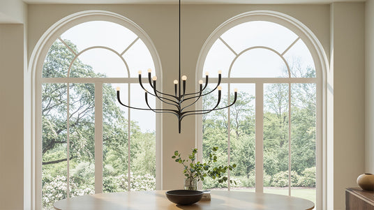 Grand Anita Chandelier in black hung above a large dining room table with tall arched window in the background