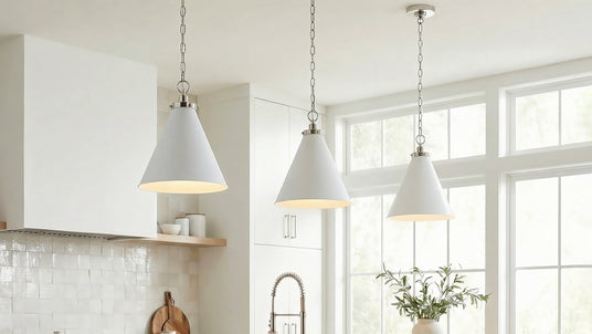 Three Classon white metal conical pendants with polished nickel hardware are hung in a bright contemporary kitchen with large windows and cream handmade tile backsplash.
