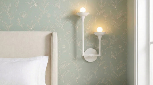 Posey 2 Light Wall Sconce next to a bed with sage green wallpaper