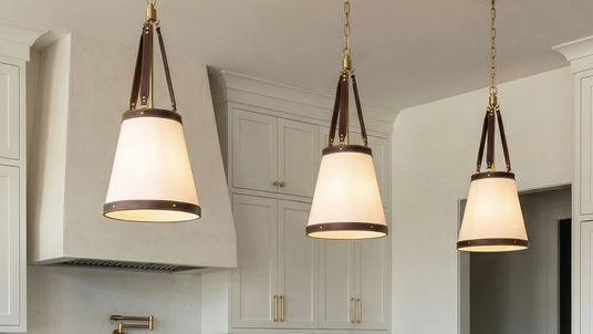 Three Spencer conical pendant lights with brown faux leather details hung in a transition kitchen.