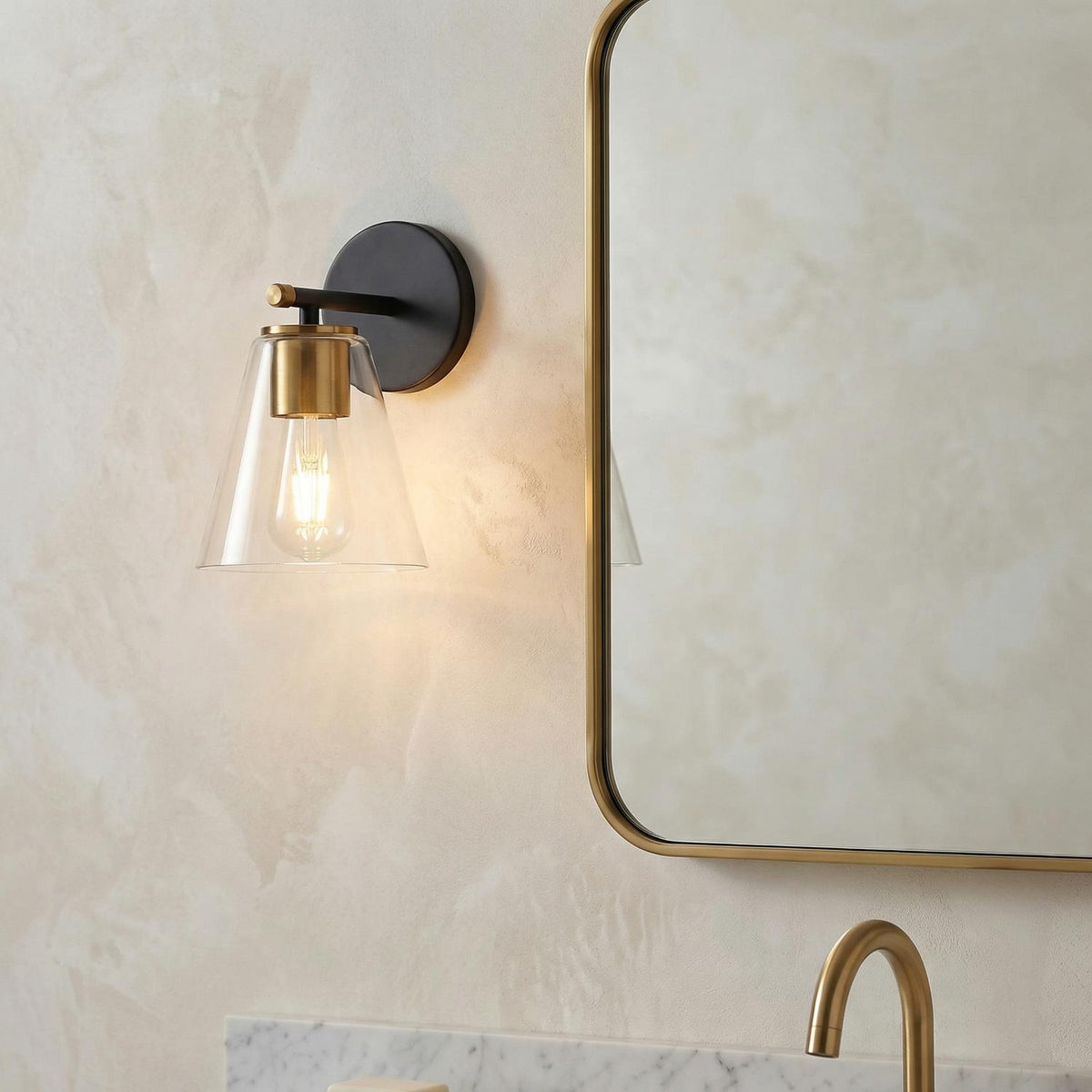 Modern Vanity Wall Sconce, Matte Black and Brass geometric Wall Sconce in a Contemporary Bathroom with a gold mirror and marble counter.