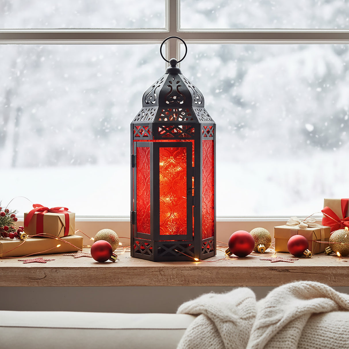 Red Glass Moroccan Christmas Lantern with twinkle lights for modern red and black holiday decor, shown in a winter window sill