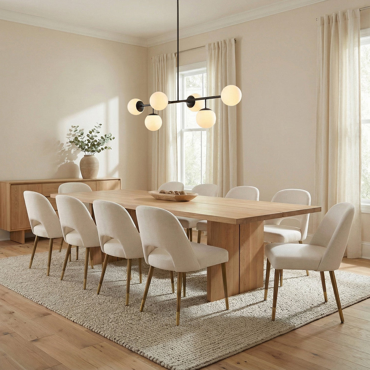 Matte Black globe linear pendant in a Transitional Dining Room with a light oak dining table and cream chairs.