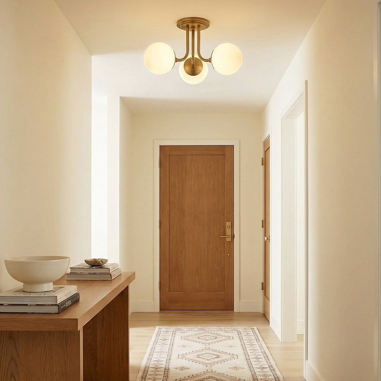 Castell 3 Globe Semi-Flush 20", Aged Brass globe flush mount in a Modern Entryway with a light wood console and patterned rug.