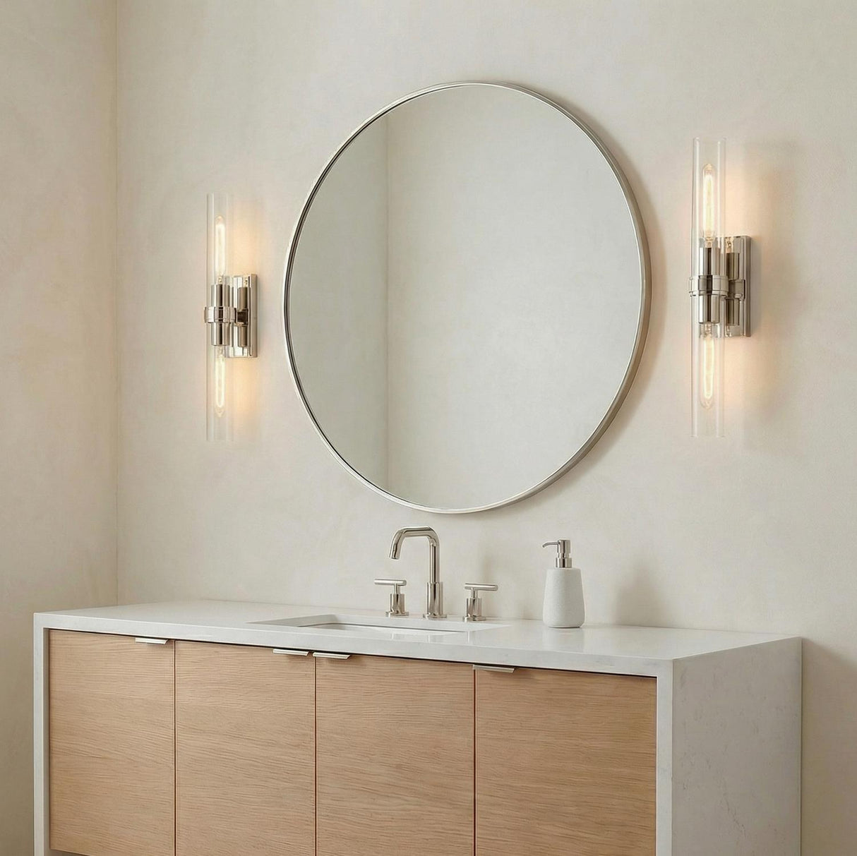 Sutton 2 Light Wall Sconce, Polished Nickel linear Wall Sconce in a Modern Bathroom with a light wood vanity and round silver mirror.