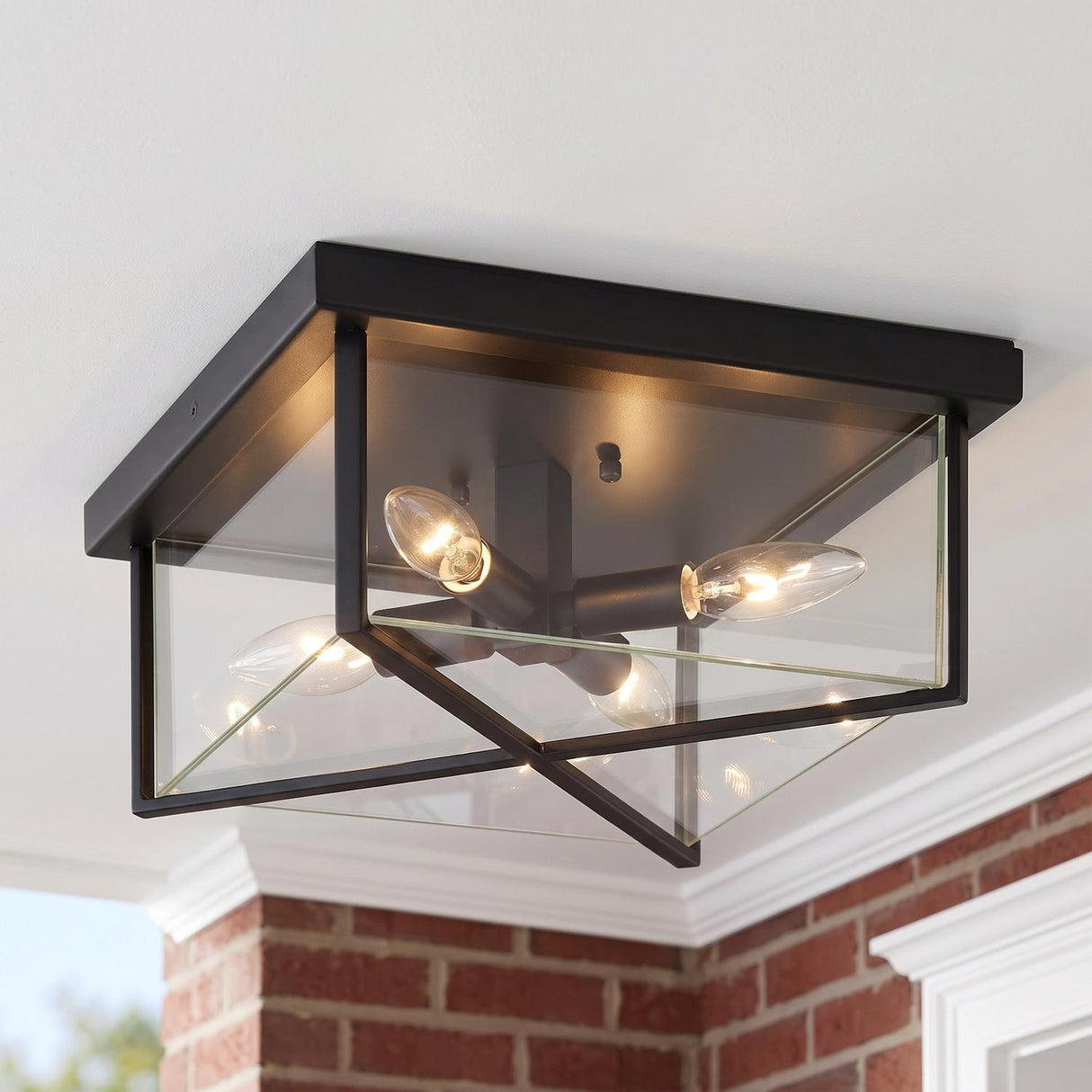 A traditional home porch featuring the Miles Indoor/Outdoor Flush Mount 12 inch in matte black glowing on a white ceiling above red brick walls and molding.
