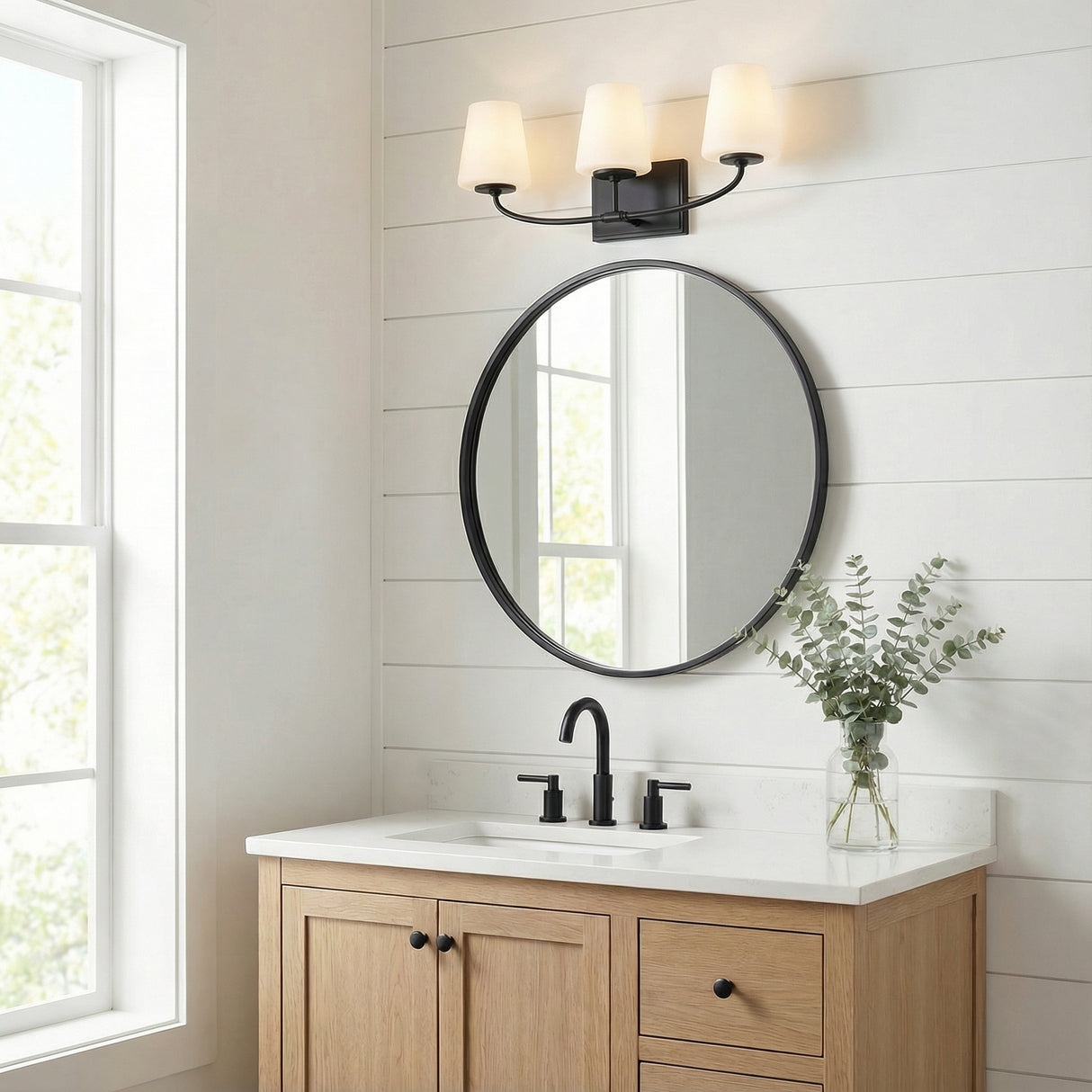 3 Light Vanity, Matte Black linear Vanity in a Modern Farmhouse Bathroom with a natural wood vanity and round mirror.