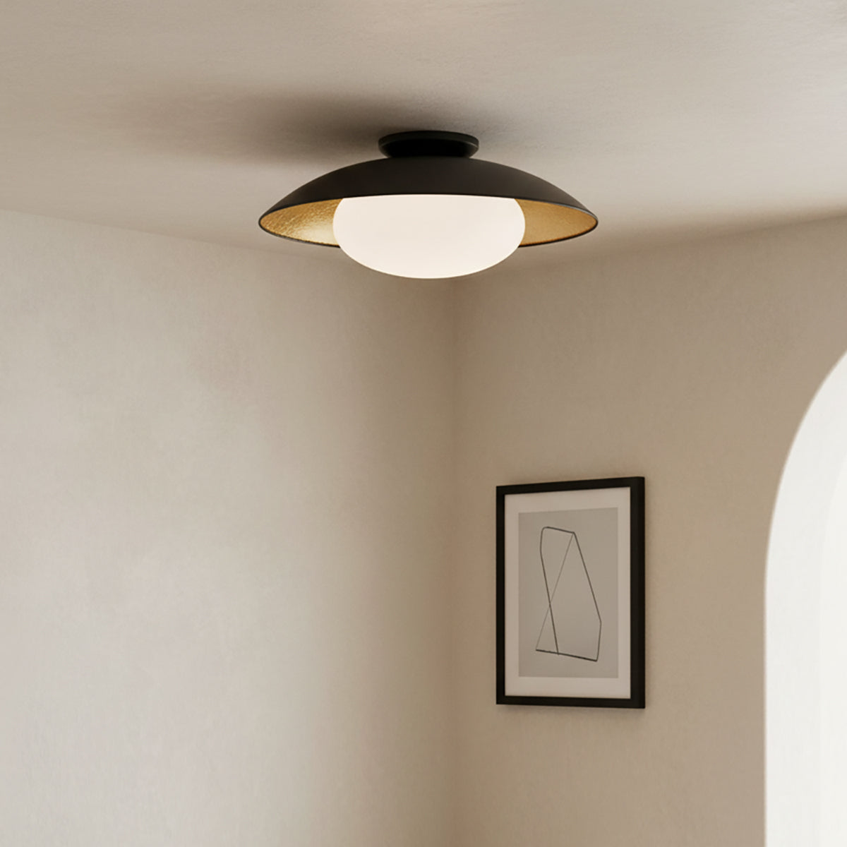 Vera Flush Mount, Large 21", Black and Gold Leaf, shown in a neutral painted room with arched hallway and art.