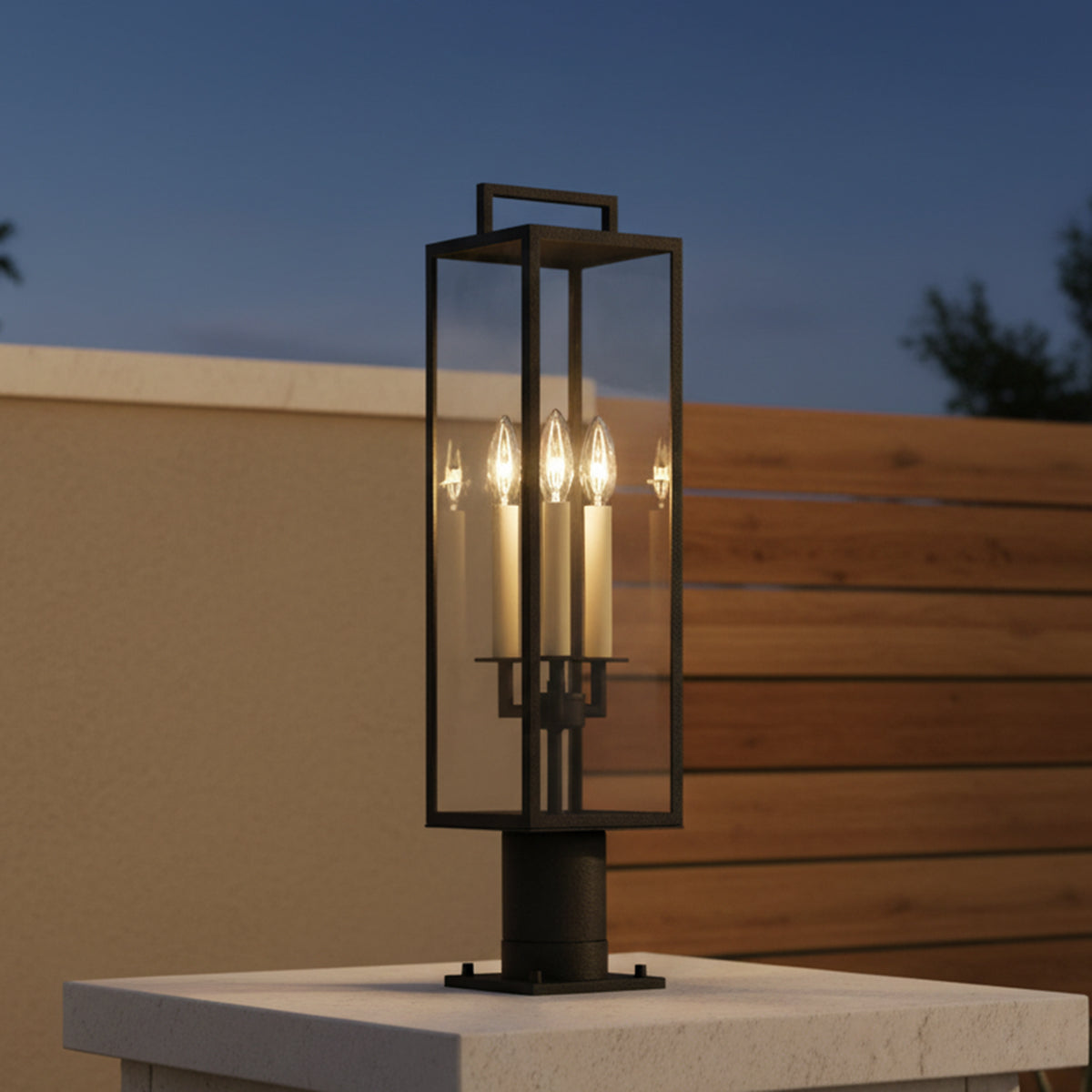 Everett Outdoor Post Light, Forged Iron Black - A black outdoor post light with candle-like bulbs atop a stone pillar with a fence in the background