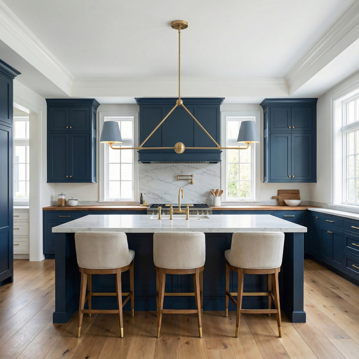Modern kitchen with blue cabinets, white island, and a french blue linear metal pendant with brass accents