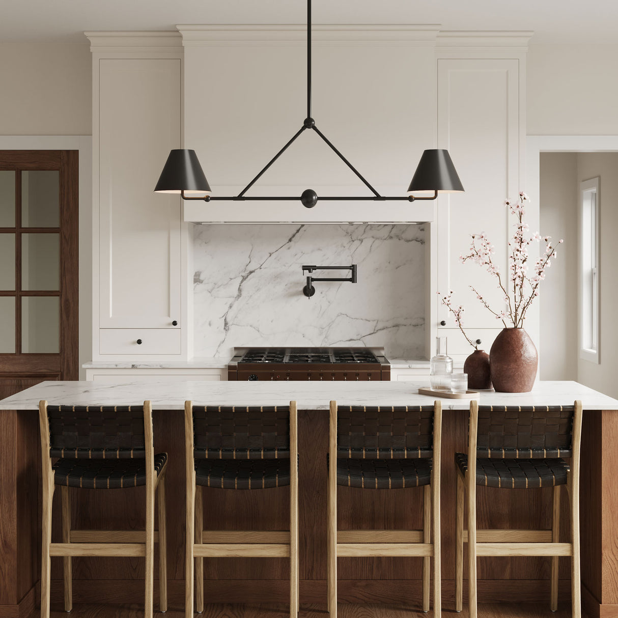 All black Banks 54" linear pendant with two shades if shown above a kitchen island with creamy white cabinetry, wood details, and white marble counter tops.