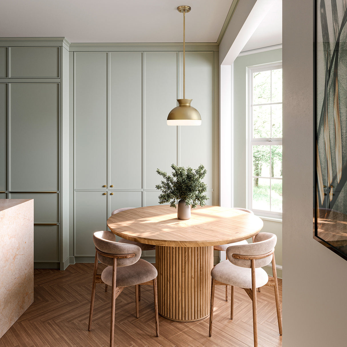 Elody 10" diameter brass pendant hung above a breakfast nook with a white oat table and floors and sage green kitchen cabinets