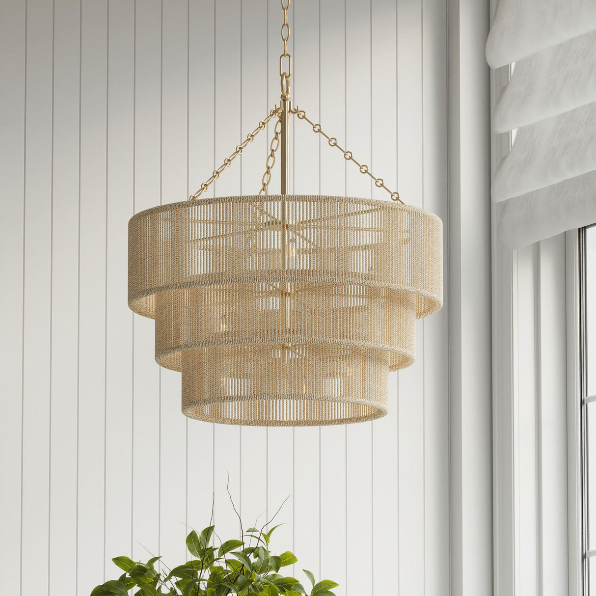 Sorelle 10 Light woven chandelier, hanging against a neutral shiplap wall with a plant in the foreground.