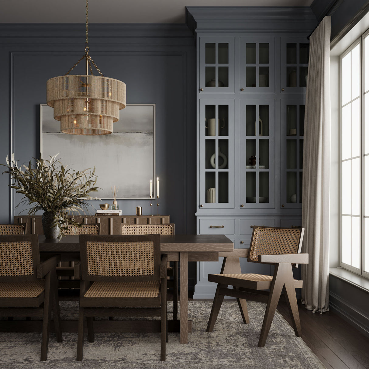 Sorelle 10 Light Chandelier 24", Jute and Soft Brass finish, is shown above a dark wood dining table in a moody room with french blue walls and rattan backed chairs.