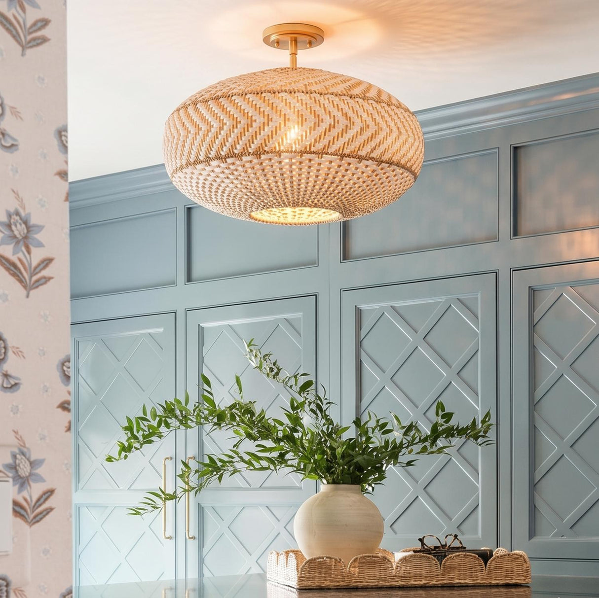 A coastal kitchen with the Sienna Semi-Flush 22", Rattan and Soft Brass fixture mounted to the ceiling above blue lattice-paneled cabinets and floral wallpaper.