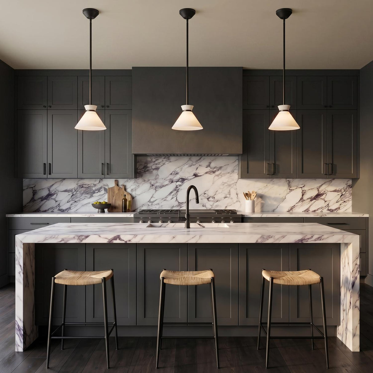 A modern kitchen with three matte black and milk glass cone pendants suspended over a white marble waterfall island and dark charcoal shaker cabinets.