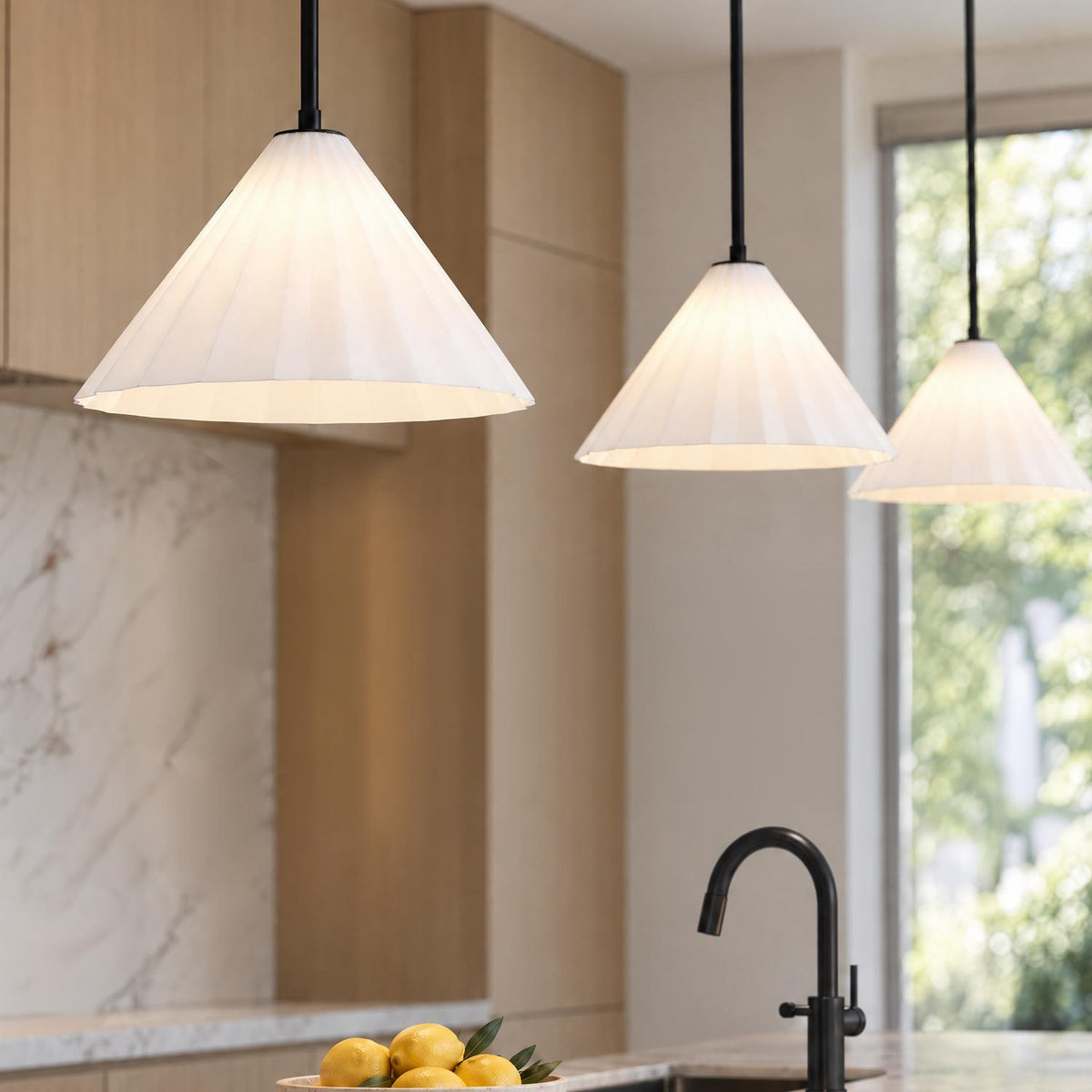 A modern kitchen featuring three white fluted glass cone pendants with matte black stems suspended over a marble island with light wood cabinetry and a black faucet.