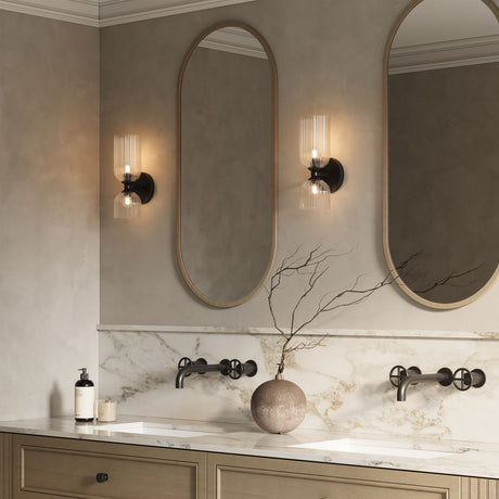 Elle Sconce in clear glass with Matte Black finish is shown in a bathroom with oval shaped mirrors and wooden details
