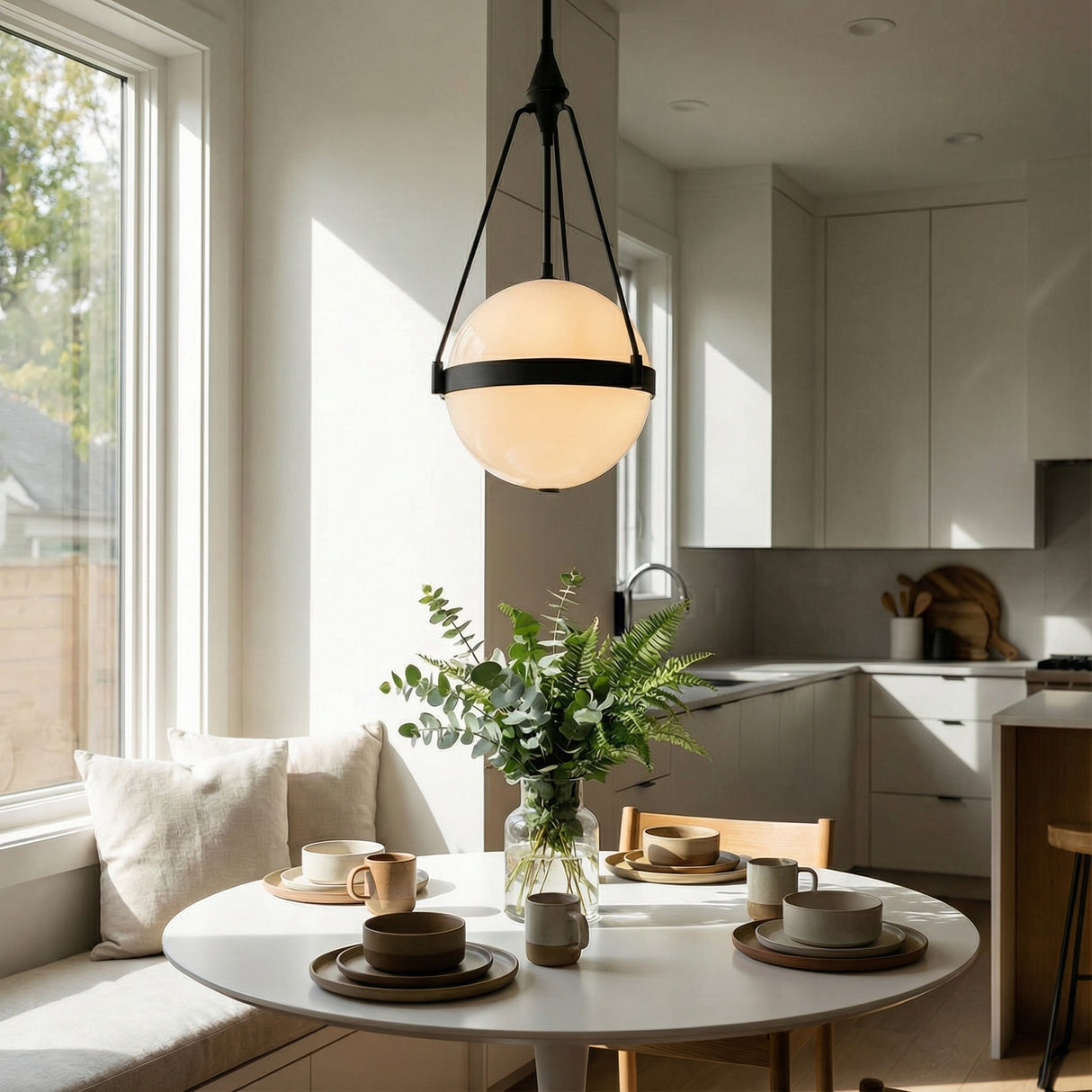 Darcy Medium Pendant 14", Matte Black and Milk Glass globe pendant in a Contemporary Kitchen with a round white table and greenery.