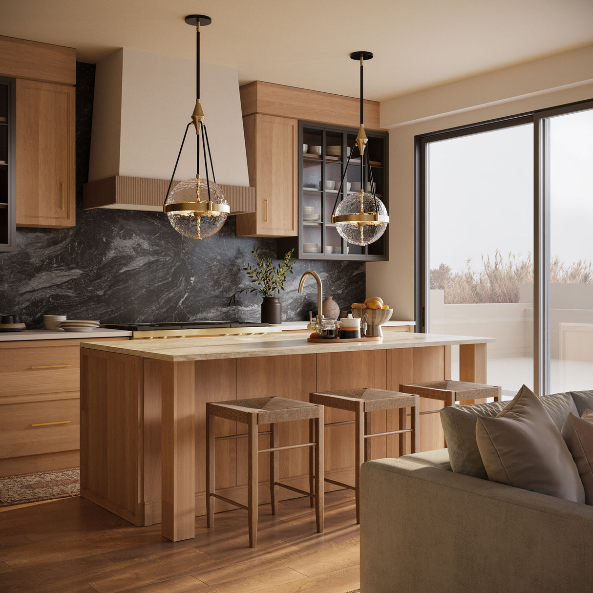 Two Darcy Large 18" Pendants in Brushed Brass and Water Glass are hung in an open concept kitchen with white oak and dark grey marble finishes.