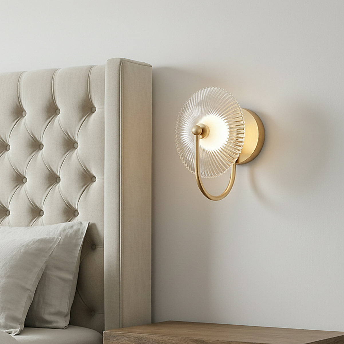 Ivan LED Curved Arm Wall Sconce, Brushed Brass geometric Wall Sconce in a Transitional Bedroom with a tufted upholstered headboard.