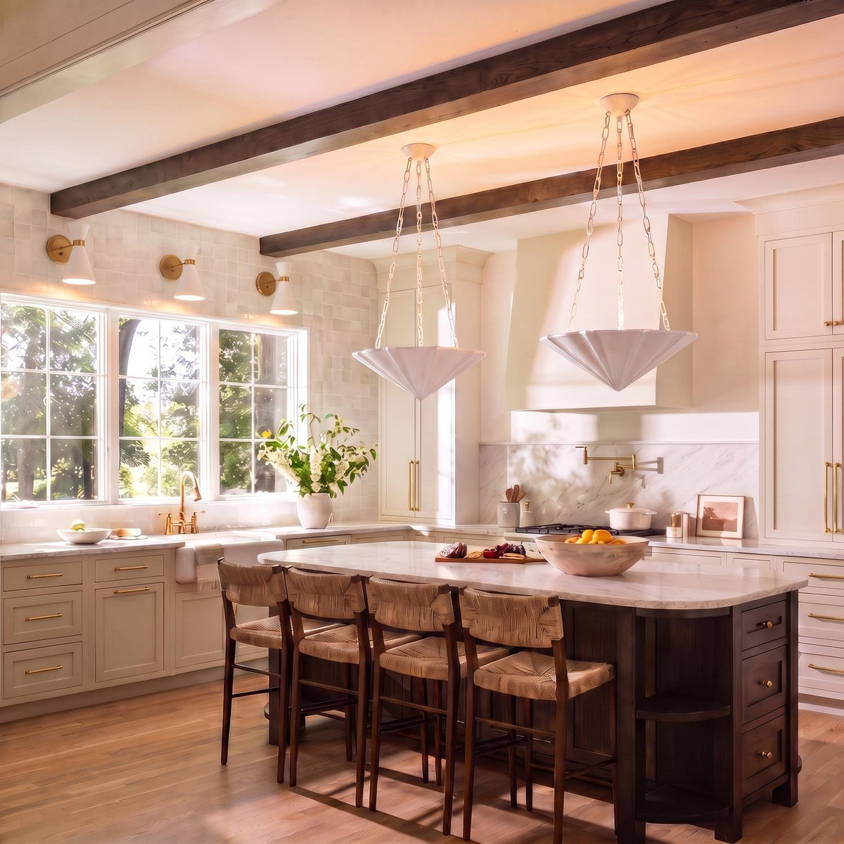 A transitional kitchen features two Cora Pendant 23", Textured White fixtures suspended over a dark wood island with a marble countertop and dark ceiling beams.