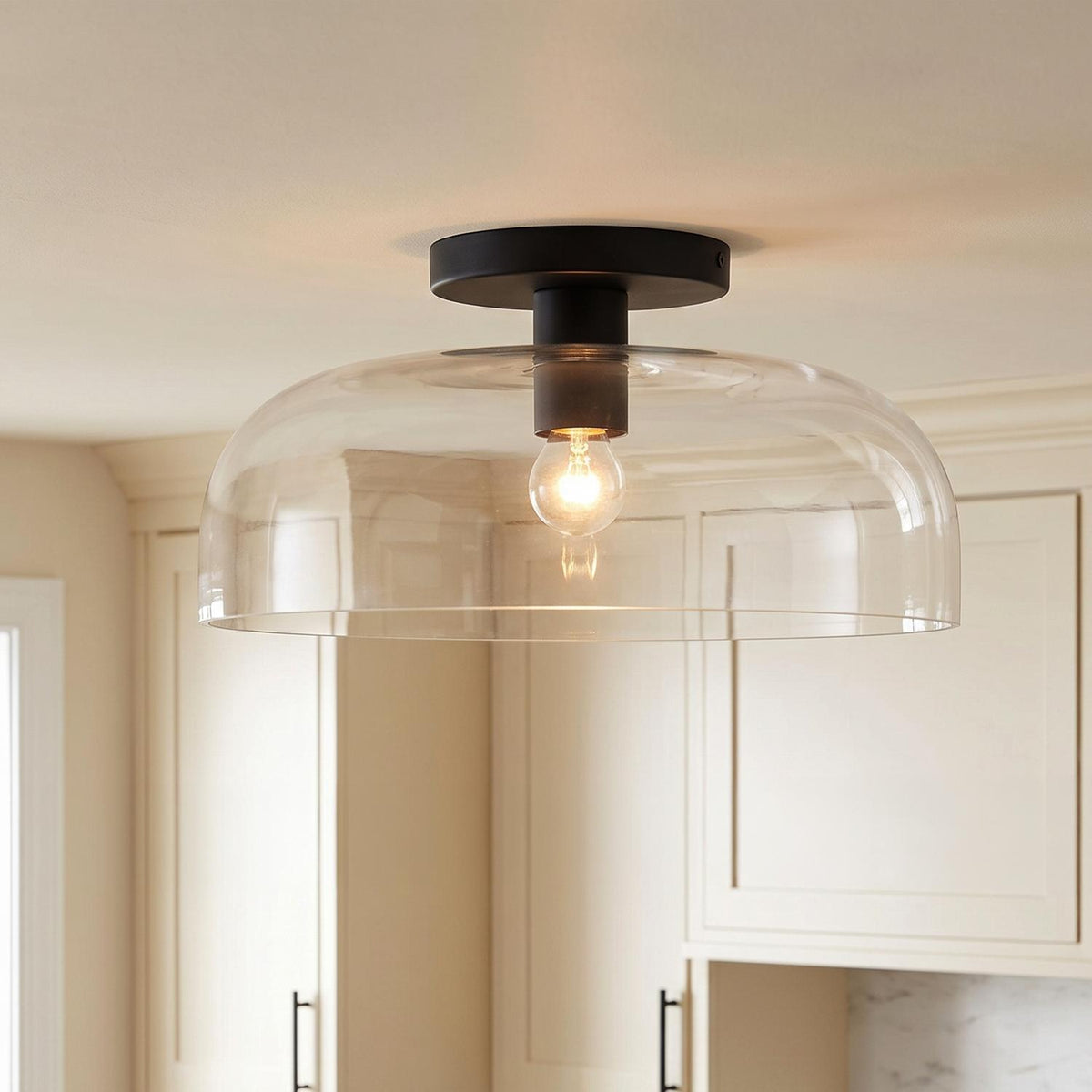 A transitional kitchen features the Bella Semi-Flush 12", Matte Black light fixture with a clear dome glass shade above off-white shaker cabinetry.