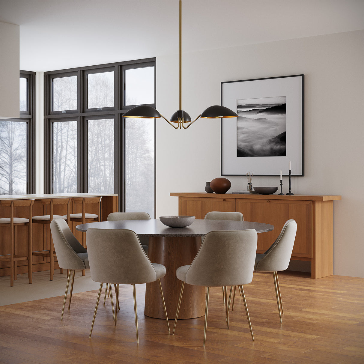 Jade 3 Light Mantis style Chandelier in Matte Black and Antique Brass finish is shown above a round modern dining room table with 6 chairs.