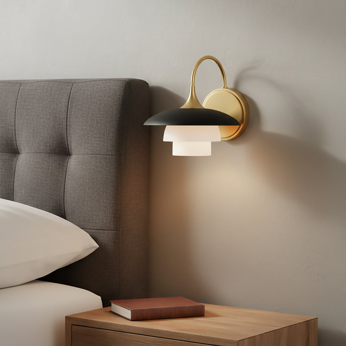 Wall-mounted Wren Wall Sconce above a nightstand next to a bed with grey fabric tufted headboard.