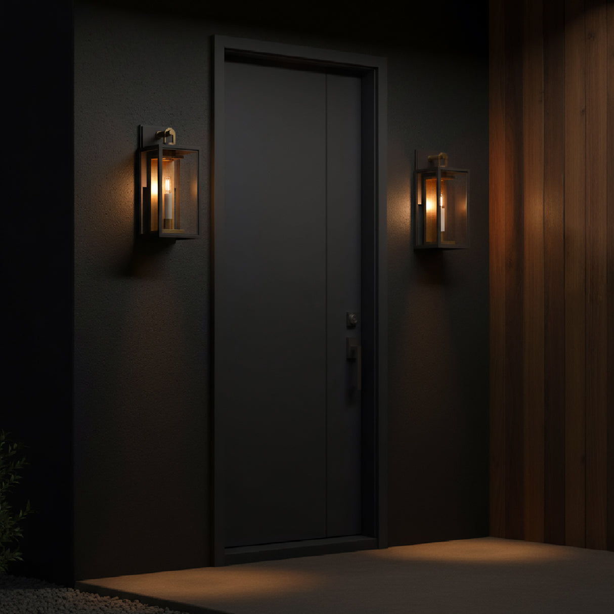 Two Orin Outdoor Small Wall Lights, Bronze with Vintage Brass Accents, shown at night on a dark grey modern facade with wood accent wall.
