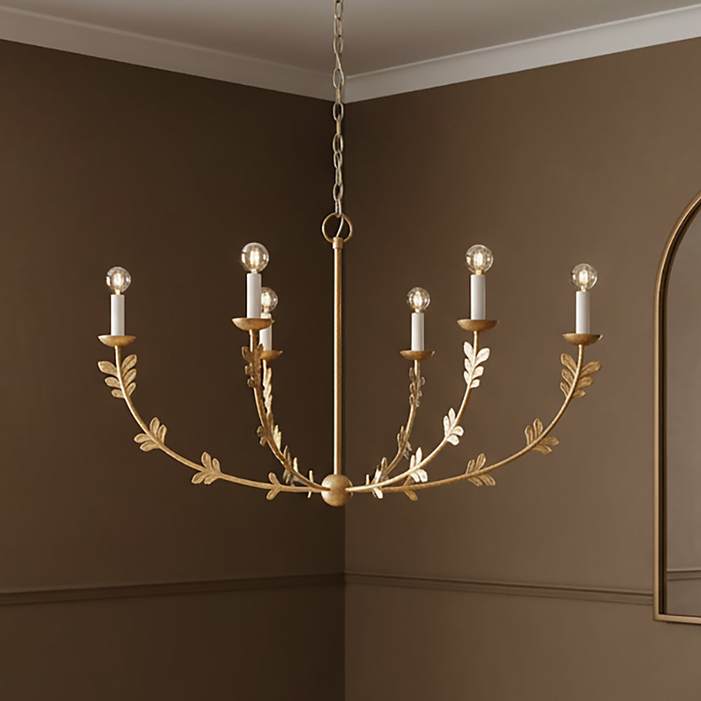 Aviva gold leaf chandelier with six candle-style lights on a brown wall background