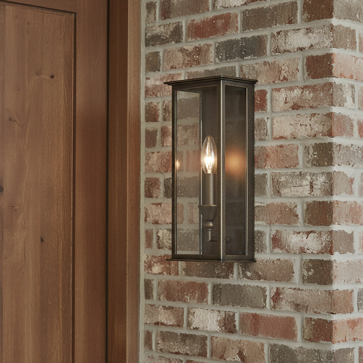 Clinton Outdoor Wall Light, Small 13" tall in Bronze finish, shown on a brick wall.