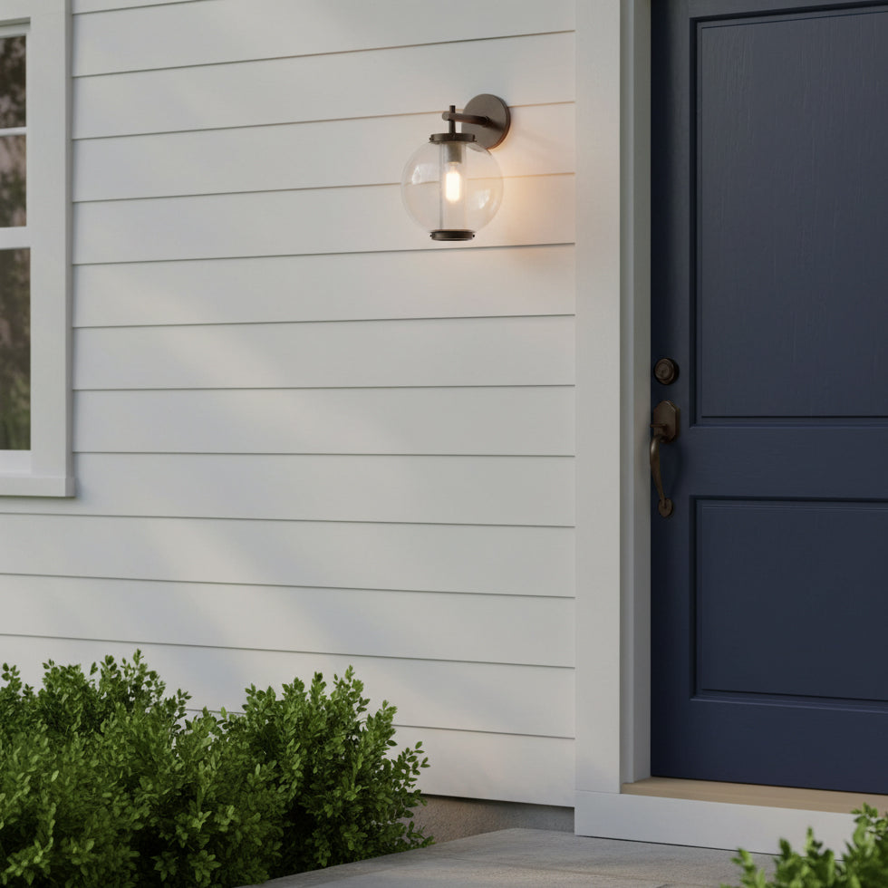 House exterior with a dark blue door and white siding, featuring a the Rogers Outdoor Wall Light, 14" in Bronze.