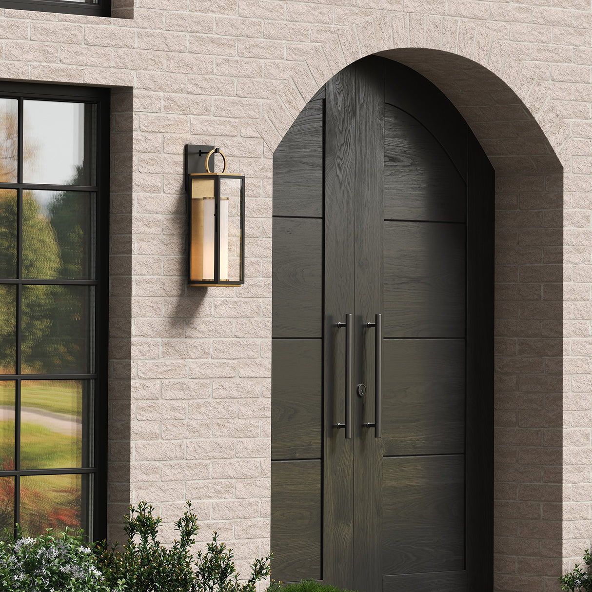 Waverly LED Outdoor Wall Light, Medium 23" tall Black with Vintage Brass Accents, shown on the front of a brick home with large arched entry doors.