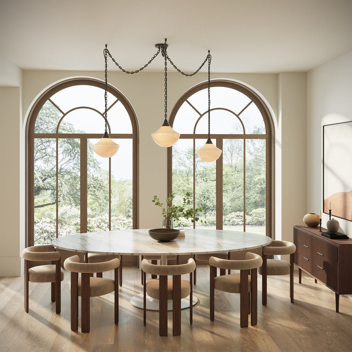 Reva 3 Light Swag Chandelier, Matte Black with Vintage Milk Glass shades, is shown hung above a large modern dining table with seating for eight.
