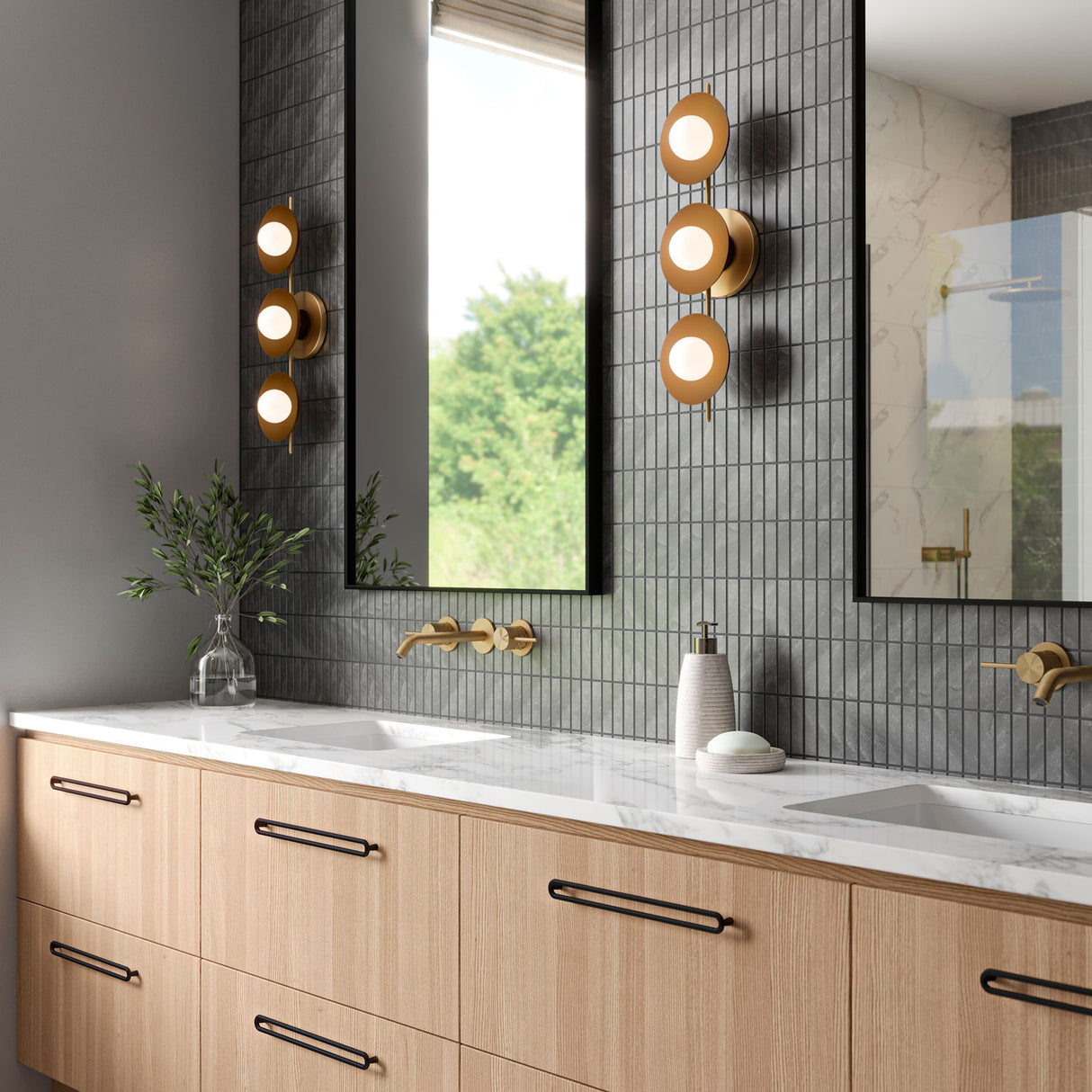 Three Globe Liam Wall light shown in a modern bathroom with grey tile and stone countertops.