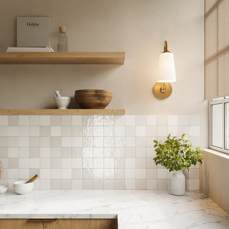 Nolan Wall Sconce 16", Aged Brass finish, shown in a kitchen with oak open shelves next to a window