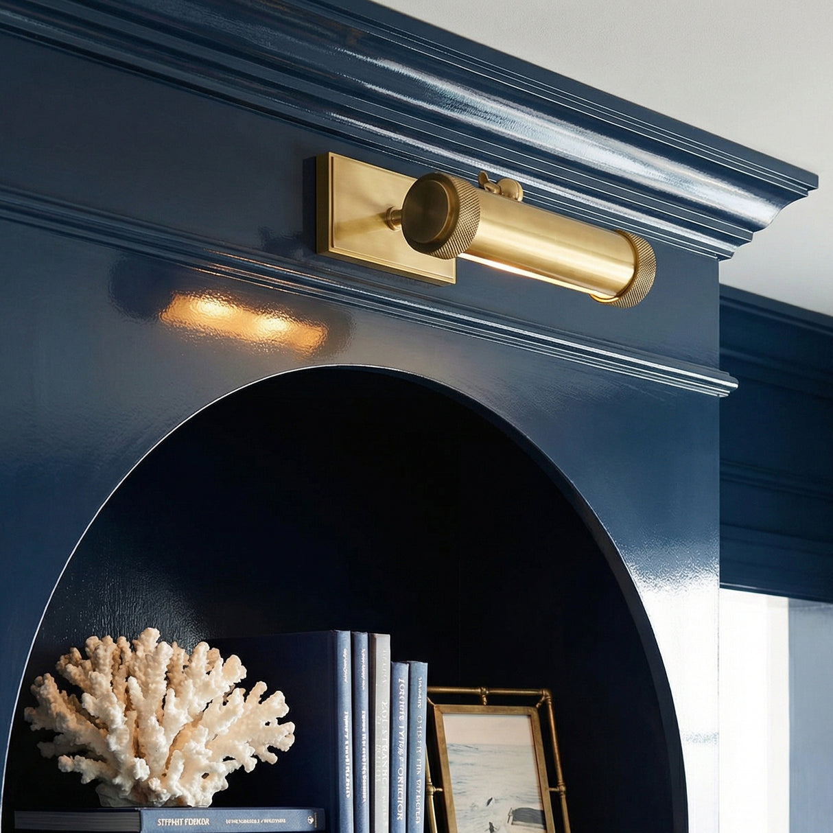 Aged Brass linear Picture Light in a Transitional Living Room with a glossy navy built-in shelf.