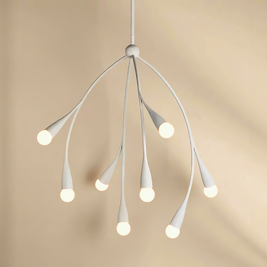Flora Pendant in textured white finish shown with lights on and glowing in front of a beige background