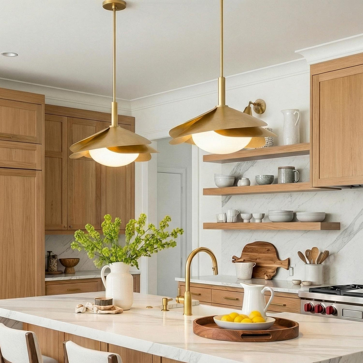 A Mid-Century kitchen with two Lola Pendant 22", Gold Leaf with Milk Glass suspended over a white marble island featuring light wood cabinets and marble backsplash.