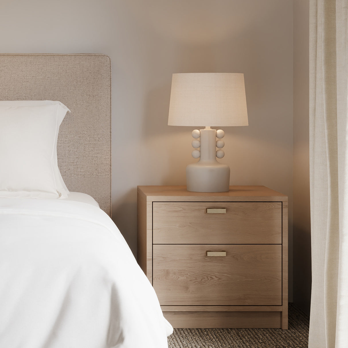 Mia Ceramic Table Lamp, Speckled White, shown on a light wood bedside table.